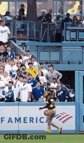 A Cheerleader Is Jumping In The Air At A Baseball Game While A Crowd Watches . GIF