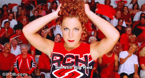 A Cheerleader Wearing A Rgh Shirt Is Standing In Front Of A Crowd GIF