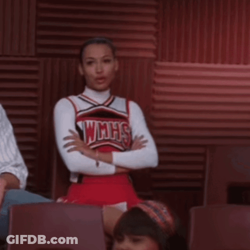 A Cheerleader Wearing A Wmhs Uniform Sits In A Chair With Her Arms Crossed GIF