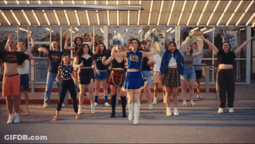 A Cheerleader With The Number 15 On Her Top Is Surrounded By Other Cheerleaders GIF