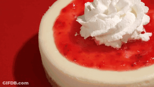 A Cheesecake With Whipped Cream On Top On A Red Background GIF