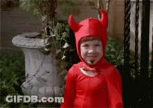 A Child In A Red Devil Costume Is Smiling . GIF