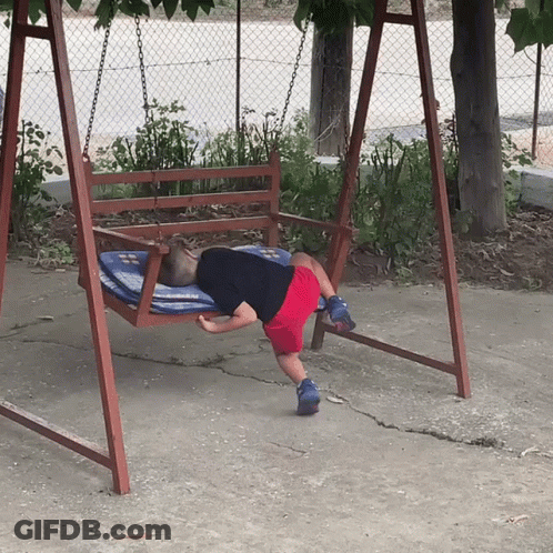 A Child Is Laying On A Wooden Swing With A Blue And White Blanket GIF