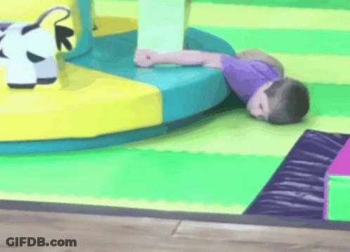 A Child Is Laying On The Floor In A Play Area GIF