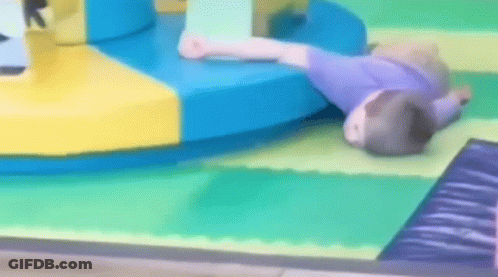 A Child Is Laying On The Floor In A Playground GIF