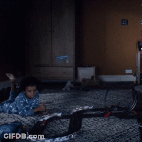 A Child Is Laying On The Floor Playing With A Toy Track GIF