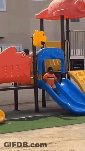 A Child Is Playing On A Slide At A Playground . GIF