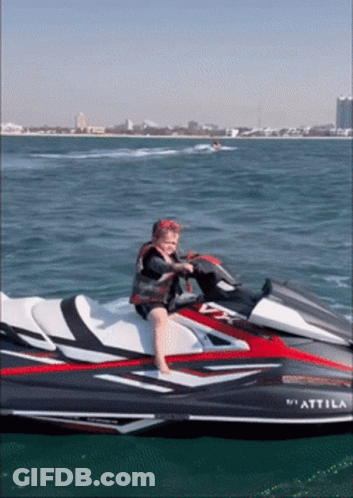 A Child Sits On A Jet Ski That Says " Attimo " On The Side GIF