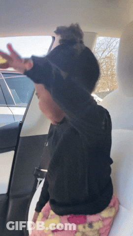A Child Sitting In The Back Seat Of A Car With Her Arms Outstretched GIF