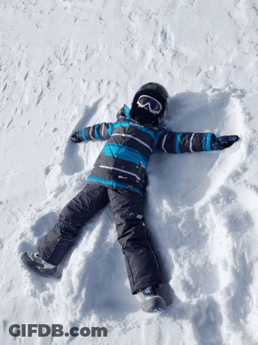 A Child Wearing A Helmet And Goggles Lays In The Snow GIF