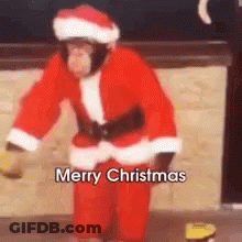 A Chimpanzee Dressed In A Santa Suit Is Dancing . GIF