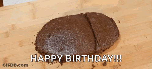 A Chocolate Cake Is Sitting On A Wooden Cutting Board With The Words `` Happy Birthday '' Written Above It . GIF