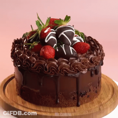 A Chocolate Cake With Strawberries On Top Is On A Cutting Board GIF