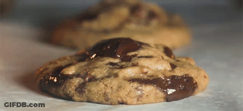 A Chocolate Chip Cookie Is Sitting On A Table GIF
