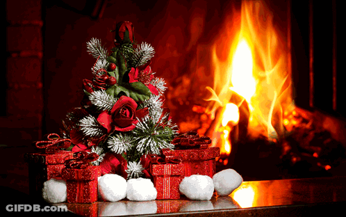 A Christmas Tree And Presents Are In Front Of A Fireplace GIF