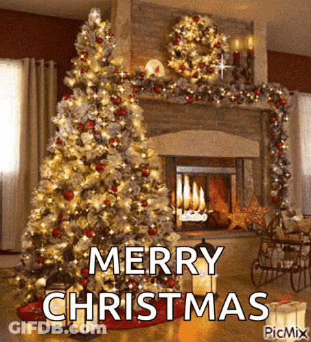 A Christmas Tree Is In Front Of A Fireplace With The Words Merry Christmas Written On It GIF