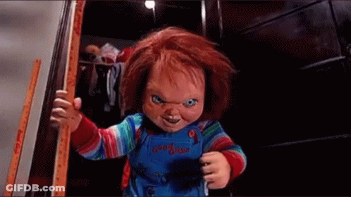 A Chucky Doll Is Standing In A Doorway Holding A Stick . GIF