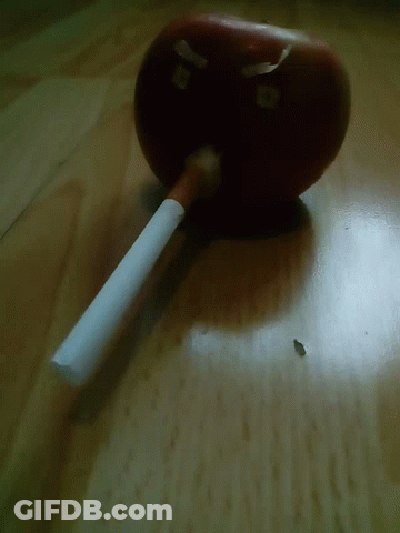 A Cigarette Is Sitting On A Table Next To An Apple That Has The Letter B On It GIF