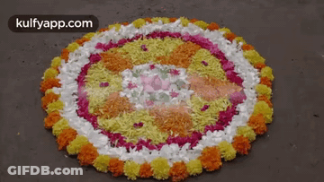 A Circular Pattern Made Of Flowers And Rice On The Ground GIF