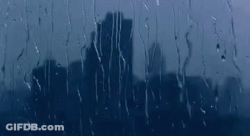 A City Skyline Is Reflected In A Window With Rain Drops On It . GIF