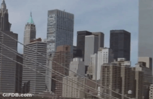 A City Skyline With A Bridge In The Foreground And One Of The Buildings Has The Word Brooklyn On The Top Of It GIF