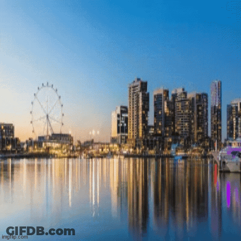 A City Skyline With A Ferris Wheel In The Foreground And A Body Of Water In The Foreground GIF