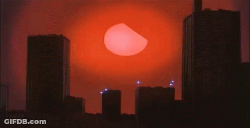 A City Skyline With A Large Red Sun Behind It GIF