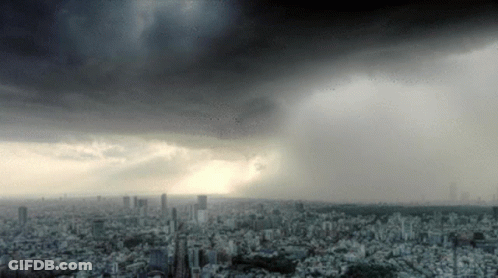 A City Under A Cloudy Sky With A Few Buildings In The Foreground GIF