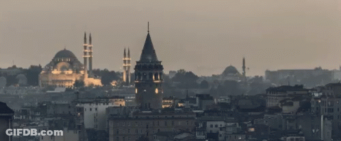 A Cityscape With A Clock Tower And A Mosque In The Distance GIF