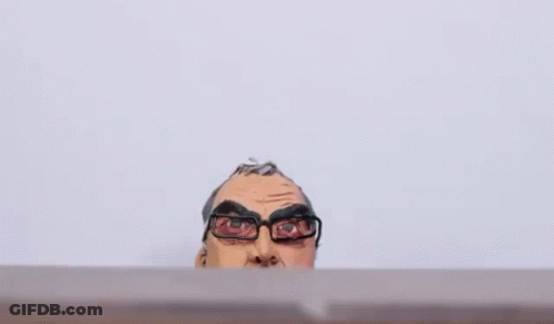 A Clay Statue Of A Man Wearing Glasses And A Hoodie Is Sitting On A Table . GIF