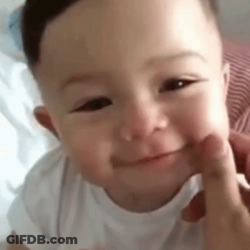 A Close Up Of A Baby 'S Face With A Person 'S Hand On It . GIF