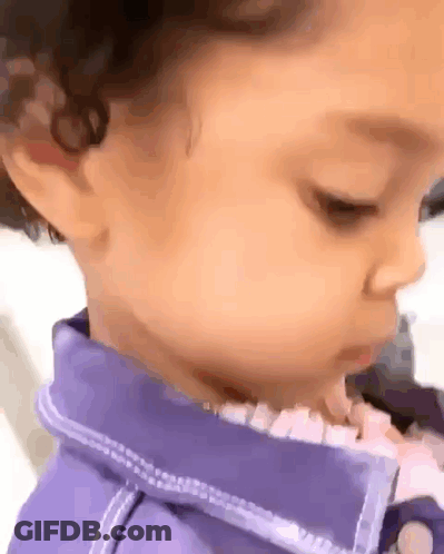 A Close Up Of A Baby 'S Face With A Purple Shirt On . GIF