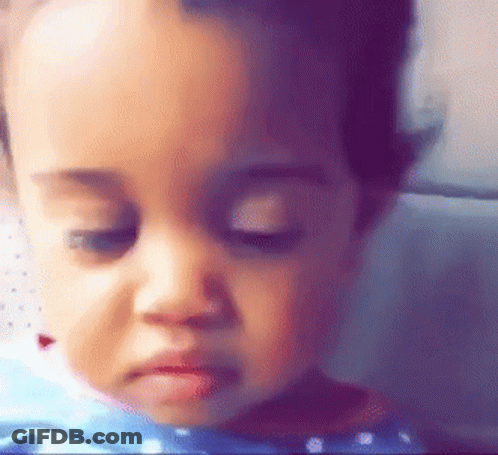 A Close Up Of A Baby 'S Face With A Sad Look On His Face . GIF