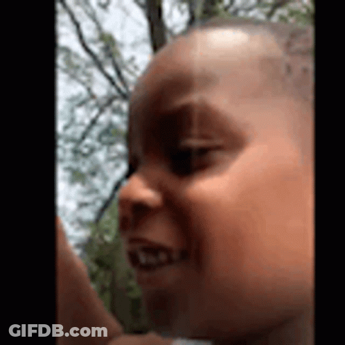 A Close Up Of A Baby 'S Face With Trees In The Background And A Blurred Background . GIF