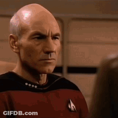A Close Up Of A Bald Man Wearing A Star Trek Uniform Looking At Someone . GIF