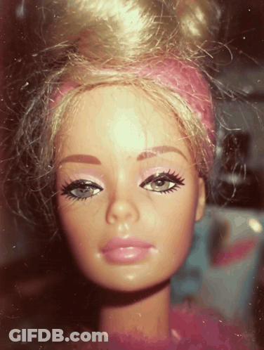 A Close Up Of A Barbie Doll With A Pink Headband On Her Head GIF