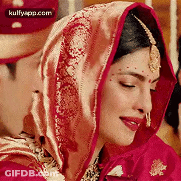 A Close Up Of A Bride Wearing A Red And Gold Dress And Veil . GIF