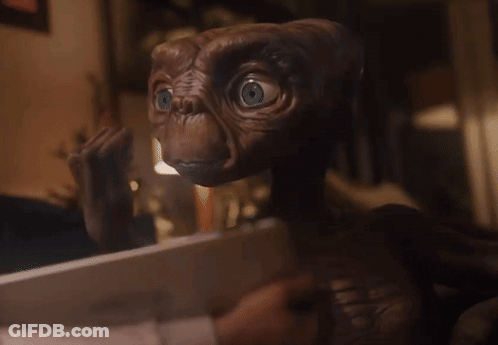 A Close Up Of A Brown Alien With Blue Eyes Looking At The Camera GIF