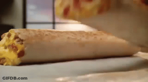 A Close Up Of A Burrito On A Table Being Eaten . GIF