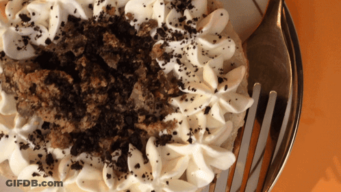 A Close Up Of A Cake With Whipped Cream And Crumbs On Top GIF
