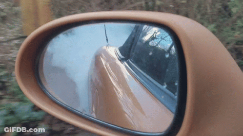 A Close Up Of A Car Rear View Mirror With A Reflection Of A Car GIF