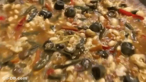 A Close Up Of A Casserole Dish With Beans , Olives , Peppers And Other Vegetables . GIF