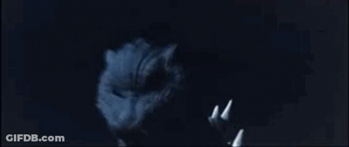 A Close Up Of A Cat 'S Face With Sharp Teeth In The Dark . GIF