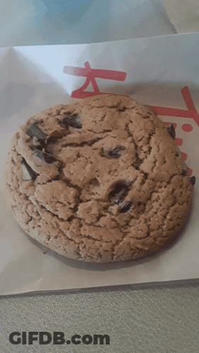 A Close Up Of A Chocolate Chip Cookie On A Piece Of Paper That Says ' Chick-Fil-A ' On It GIF