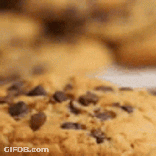 A Close Up Of A Chocolate Chip Cookie On A Plate With Other Cookies . GIF