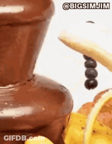 A Close Up Of A Chocolate Fountain With Bananas And Berries . GIF