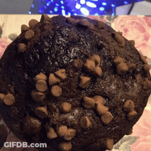 A Close Up Of A Chocolate Muffin With Chocolate Chips On It GIF