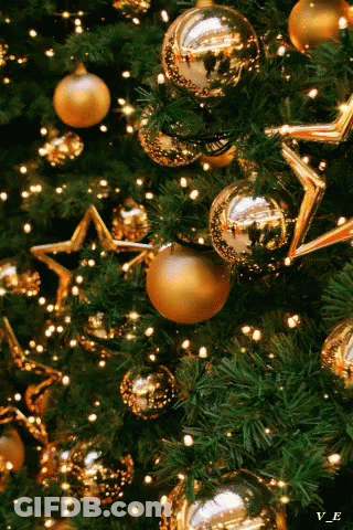 A Close Up Of A Christmas Tree With Gold Ornaments And Lights GIF