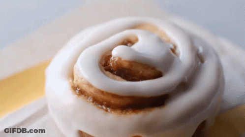 A Close Up Of A Cinnamon Roll With Icing GIF