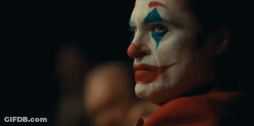 A Close Up Of A Clown 'S Face In A Dark Room . GIF